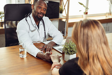 Image showing African-american doctor consulting for patient, working in cabinet, close up