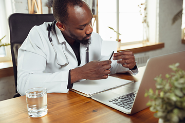 Image showing African-american doctor consulting for patient, working in cabinet, close up