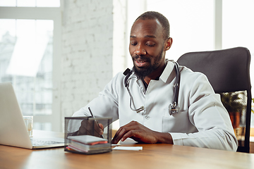 Image showing African-american doctor consulting for patient, working in cabinet, close up