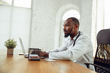 Image showing African-american doctor consulting for patient, working in cabinet, close up