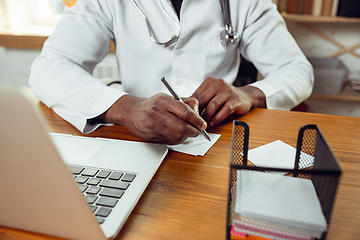 Image showing African-american doctor consulting for patient, working in cabinet, close up