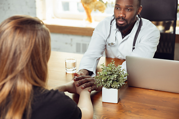 Image showing African-american doctor consulting for patient, working in cabinet, close up