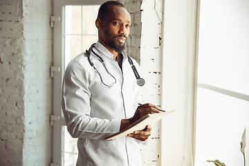 Image showing African-american doctor consulting, working in cabinet, close up