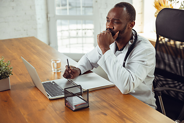 Image showing African-american doctor consulting for patient, working in cabinet, close up