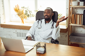 Image showing African-american doctor consulting for patient, working in cabinet, close up