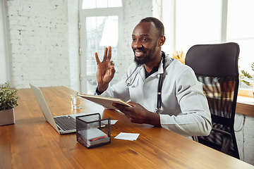 Image showing African-american doctor consulting for patient, working in cabinet, close up