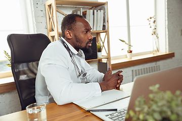 Image showing African-american doctor consulting for patient, working in cabinet, close up