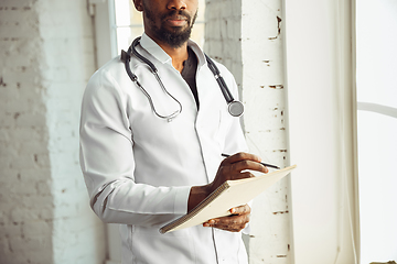 Image showing African-american doctor consulting, working in cabinet, close up