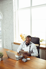 Image showing African-american doctor consulting for patient, working in cabinet, close up