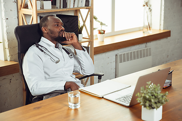 Image showing African-american doctor consulting for patient, working in cabinet, close up