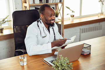 Image showing African-american doctor consulting for patient, working in cabinet, close up