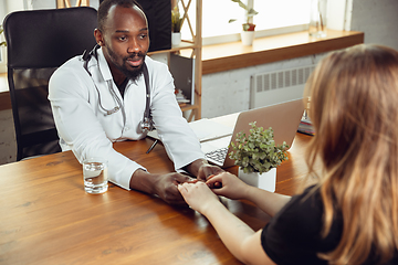 Image showing African-american doctor consulting for patient, working in cabinet, close up