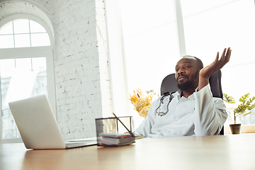 Image showing African-american doctor consulting for patient, working in cabinet, close up