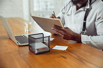 Image showing African-american doctor consulting for patient, working in cabinet, close up