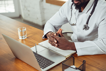 Image showing African-american doctor consulting for patient, working in cabinet, close up