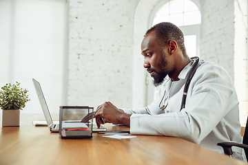 Image showing African-american doctor consulting for patient, working in cabinet, close up