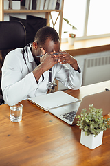 Image showing African-american doctor consulting for patient, working in cabinet, close up