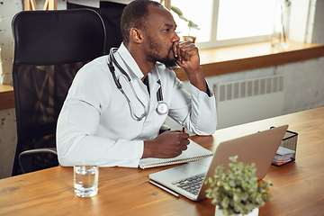 Image showing African-american doctor consulting for patient, working in cabinet, close up