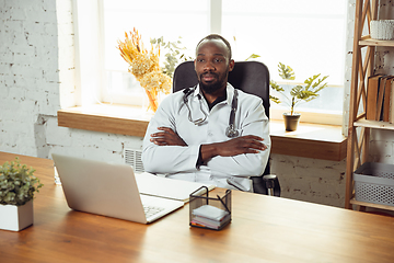 Image showing African-american doctor consulting for patient, working in cabinet, close up