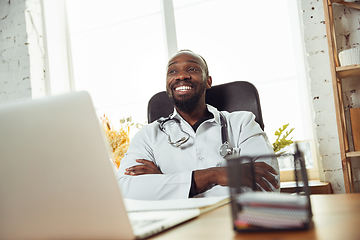 Image showing African-american doctor consulting for patient, working in cabinet, close up