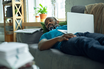 Image showing African-american man staying at home during quarantine because of coronavirus spreading