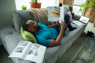 Image showing African-american man staying at home during quarantine because of coronavirus spreading