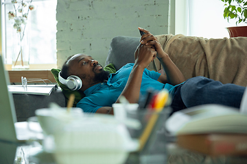 Image showing African-american man staying at home during quarantine because of coronavirus spreading