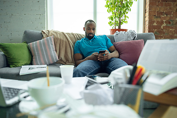 Image showing African-american man staying at home during quarantine because of coronavirus spreading