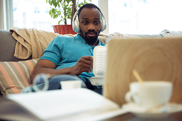 Image showing African-american man staying at home during quarantine because of coronavirus spreading