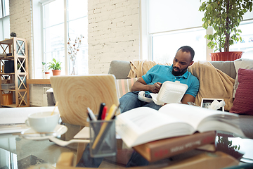 Image showing African-american man staying at home during quarantine because of coronavirus spreading