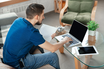 Image showing Young focused man studying at home during online courses or free information by hisself