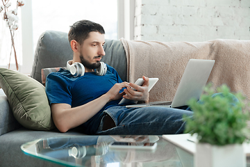 Image showing Young focused man studying at home during online courses or free information by hisself