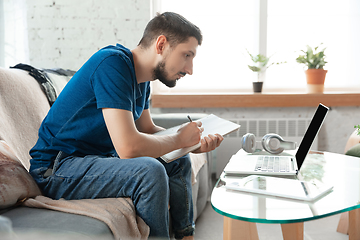 Image showing Young focused man studying at home during online courses or free information by hisself