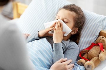 Image showing mother and ill little daughter blowing nose in bed