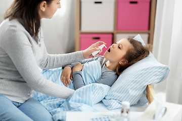 Image showing mother with oral spray treats sick little daughter