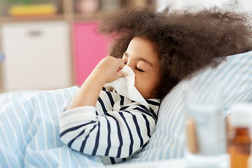 Image showing sick girl lying in bed and blowing nose at home