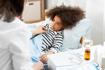 Image showing doctor with stethoscope and sick girl in bed