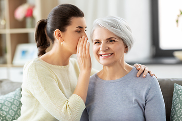 Image showing adult daughter whispering secret to senior mother