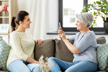 Image showing senior mother photographing adult daughter at home