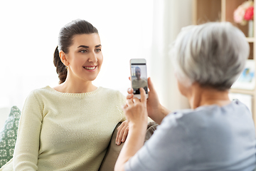 Image showing senior mother photographing adult daughter at home