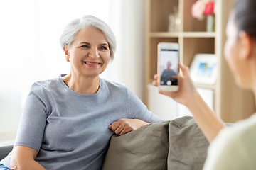 Image showing adult daughter photographing senior mother at home