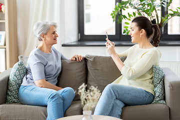 Image showing adult daughter photographing senior mother at home