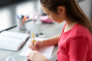 Image showing student girl with ruler drawing line in notebook