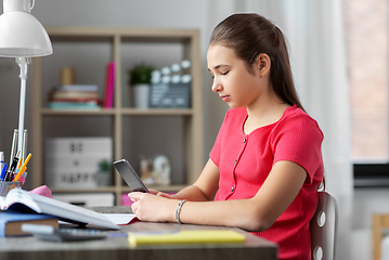 Image showing girl with smartphone distracting from homework