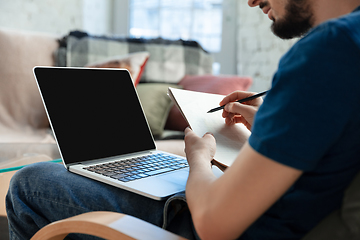 Image showing Young focused man studying at home during online courses or free information by hisself