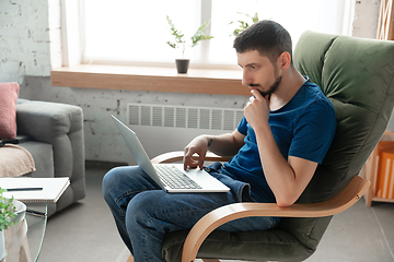 Image showing Young focused man studying at home during online courses or free information by hisself