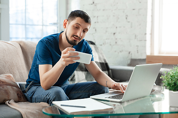 Image showing Young focused man studying at home during online courses or free information by hisself