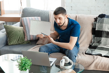 Image showing Young focused man studying at home during online courses or free information by hisself