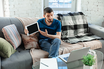 Image showing Young focused man studying at home during online courses or free information by hisself