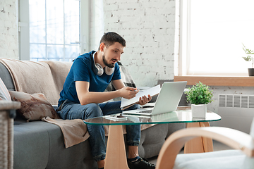 Image showing Young focused man studying at home during online courses or free information by hisself